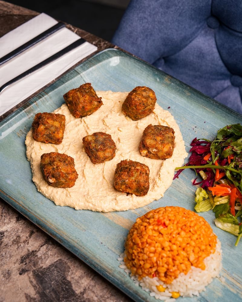Falafel served on a bed of hummus with bulgur wheat and salad