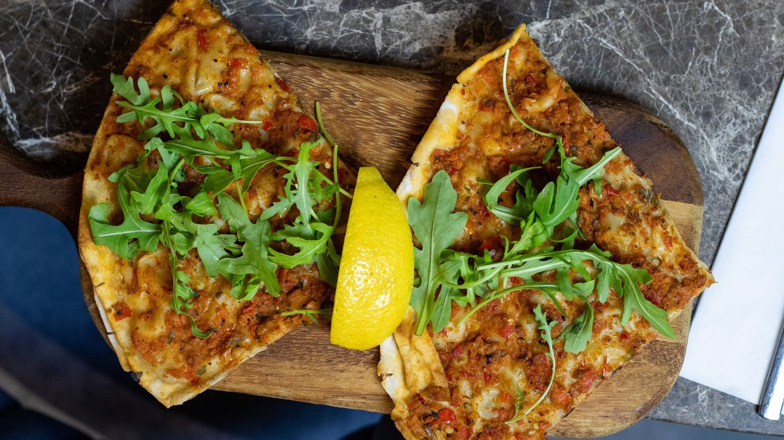 Freshly baked lahmacun with rocket and lemon, ready for takeaway
